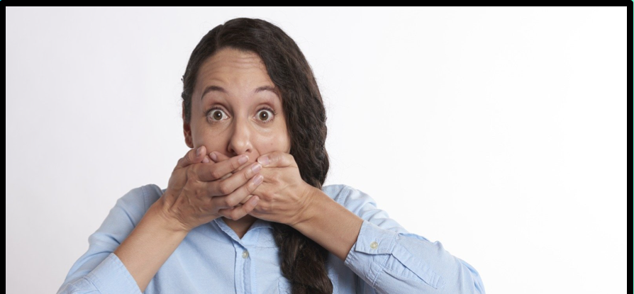 A woman with hands over her mouth looking shocked