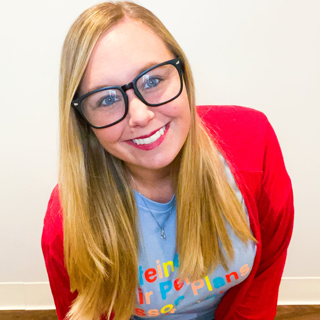 Heather smiling with glasses and a blue shirt with a red cardigan 